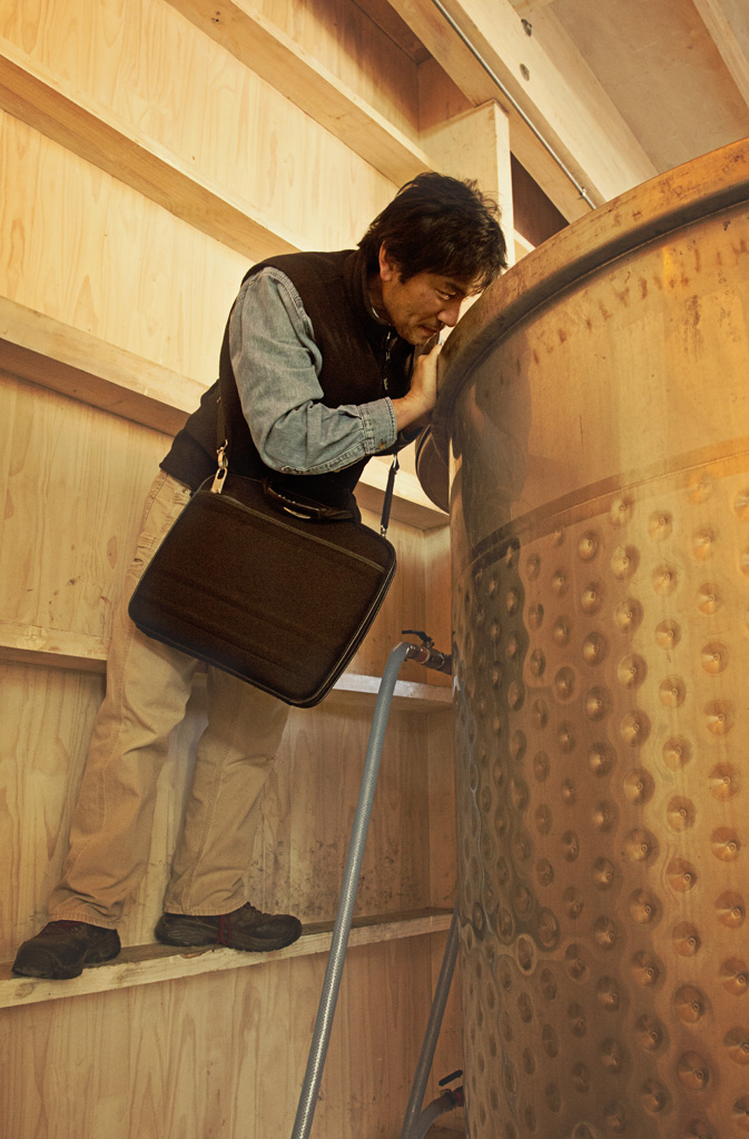 Leaning into an open top tank to check on fermenting Syrah. Laptop computer thankfully remains dry outside the tank.